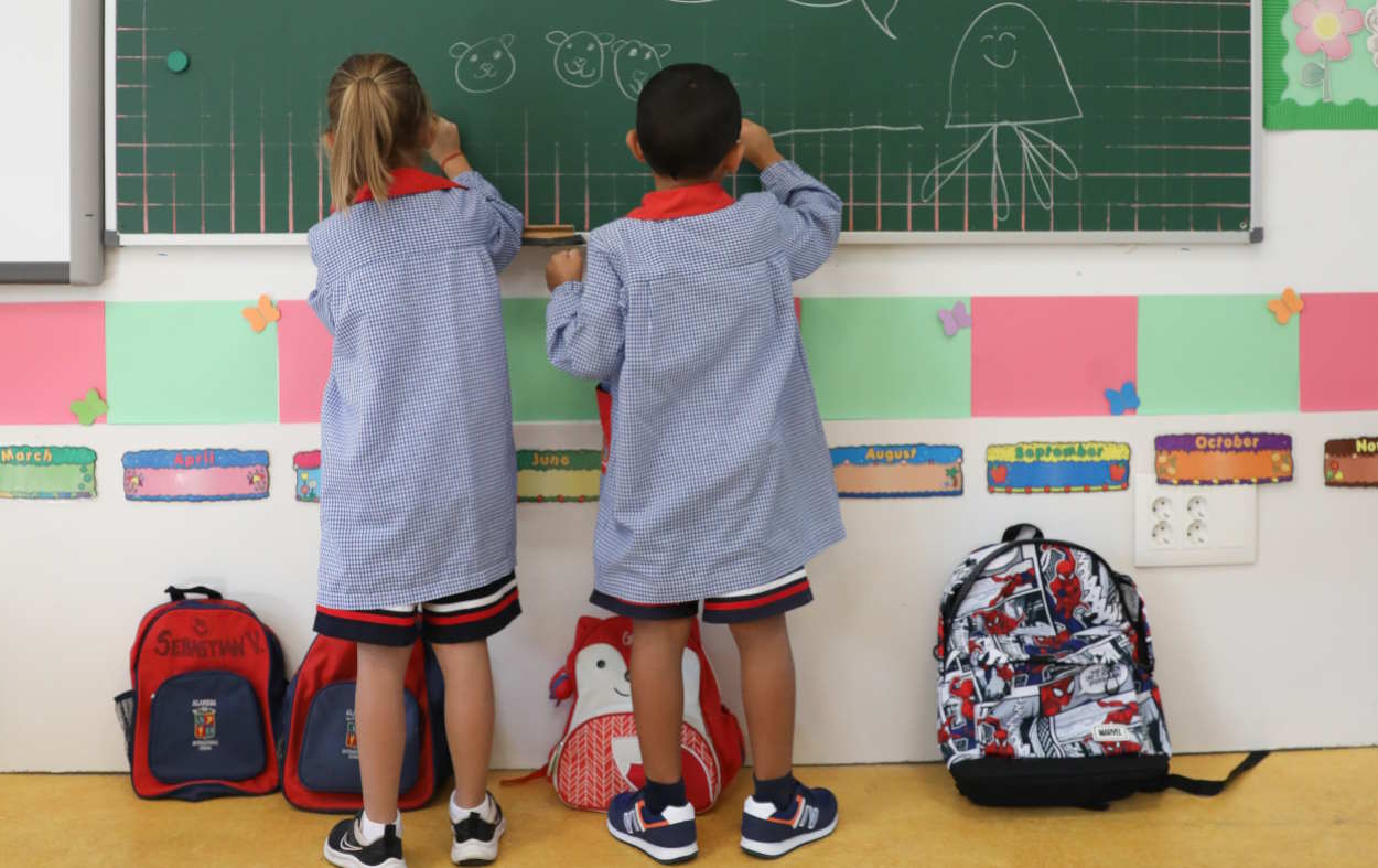 Dos niños pintando en la pizarra en un colegio. EP