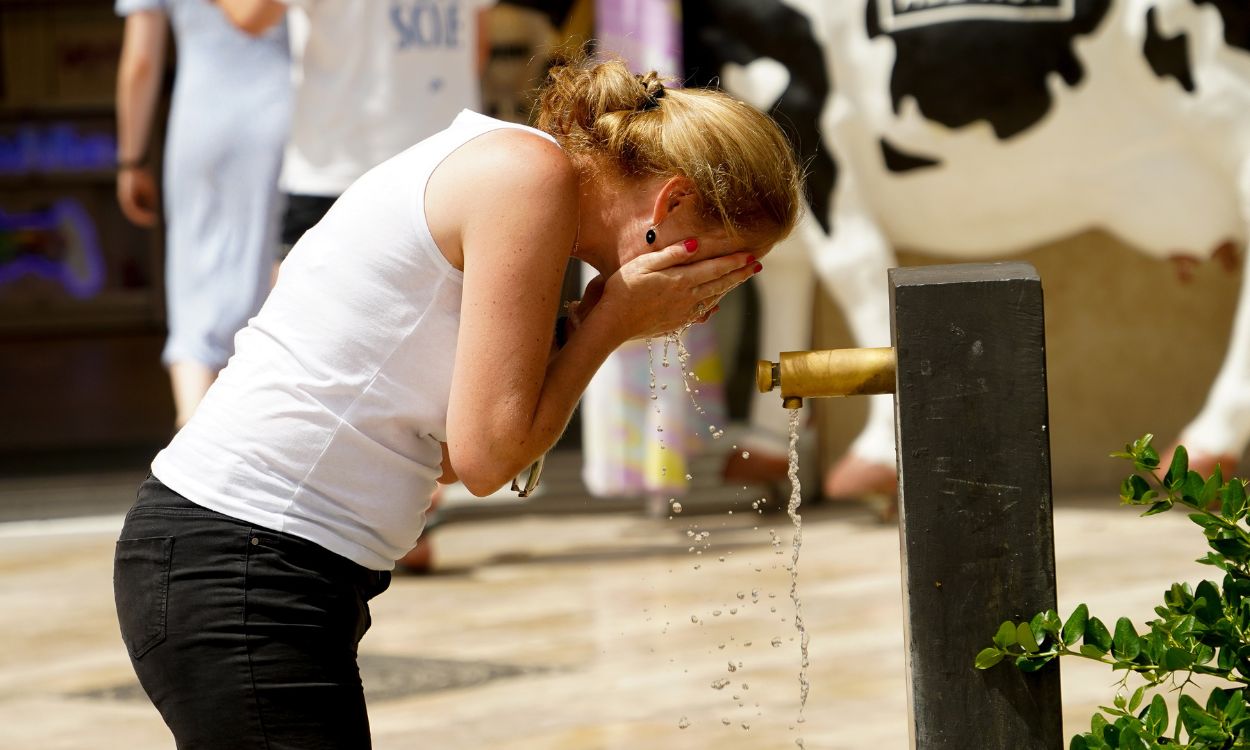 Una mujer se refresca en una fuente para combatir el calor en agosto de 2023, en Valencia. EP