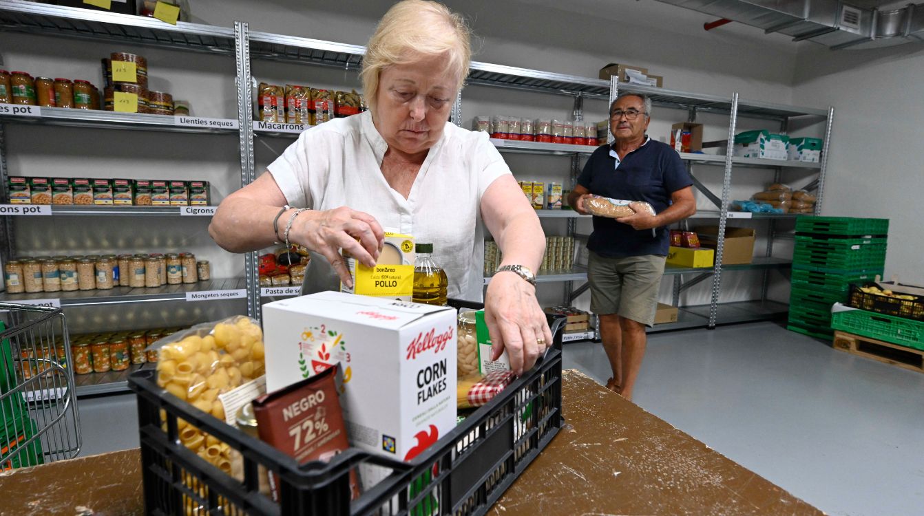 Montse, voluntaria de la entidad social De Veí a Veí, junto a su compañero Ramón en el almacén de alimentos.