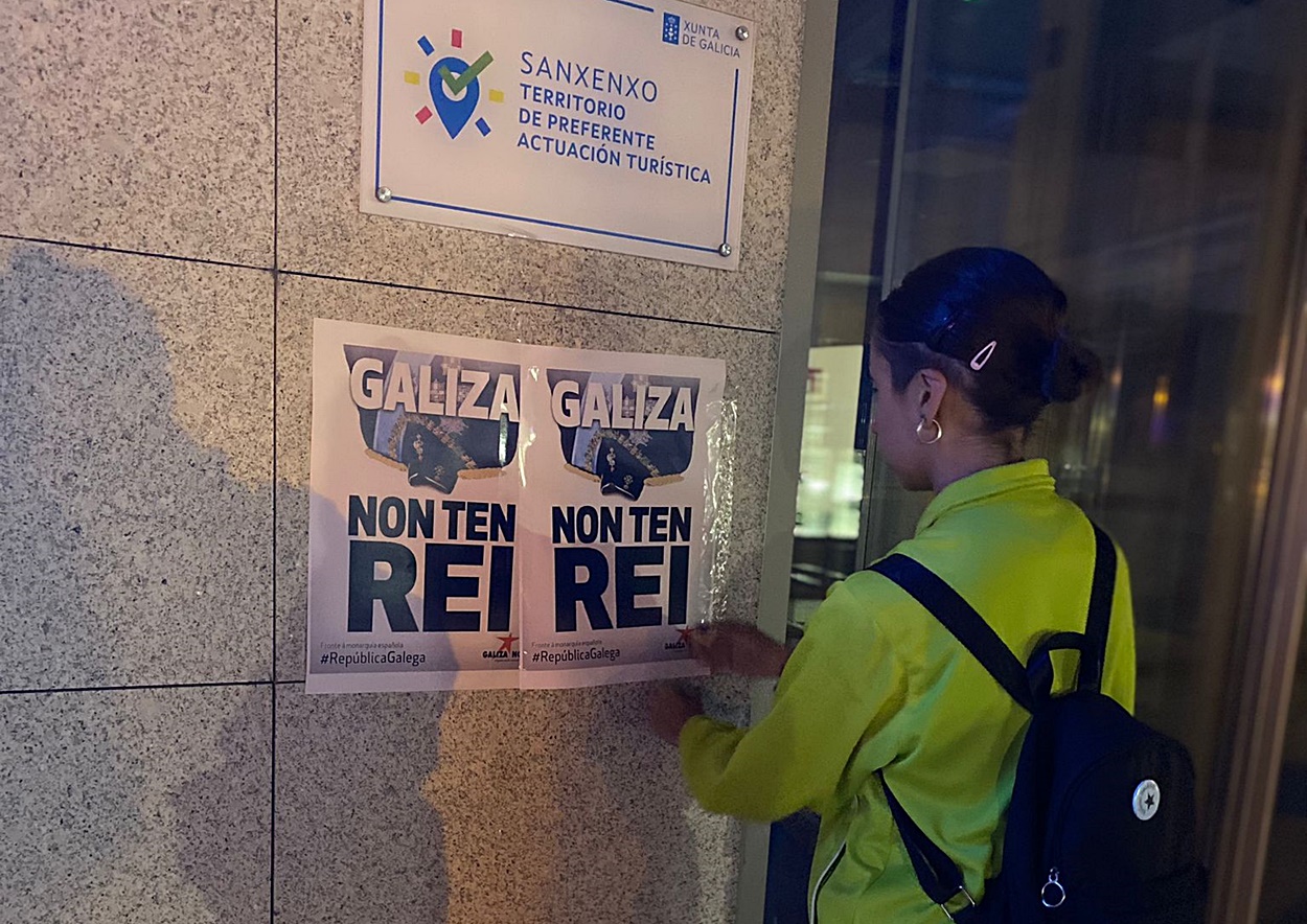 Imagen de una de las jóvenes de Galiza Nova poniendo carteles en Sanxenxo contra la presencia del rey emérito (Foto: Galiza Nova).