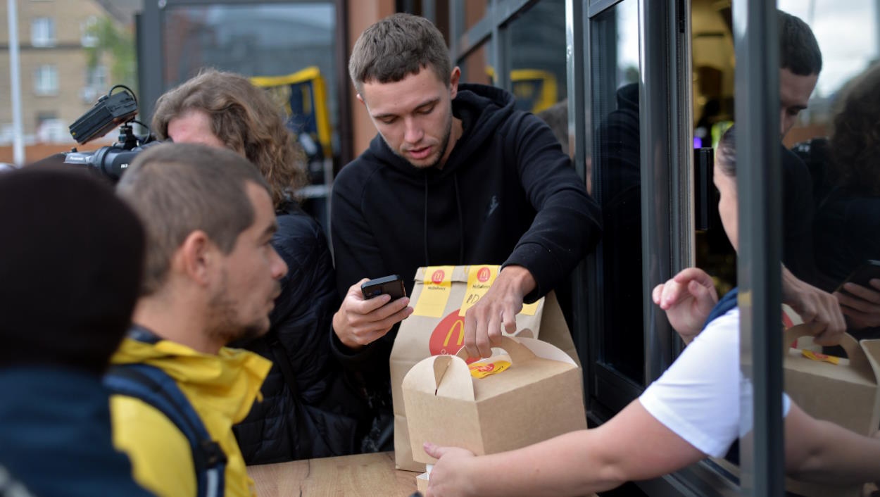 Un joven recoge un menú Big Mac de McDonald's con un iPhone en la mano. EP