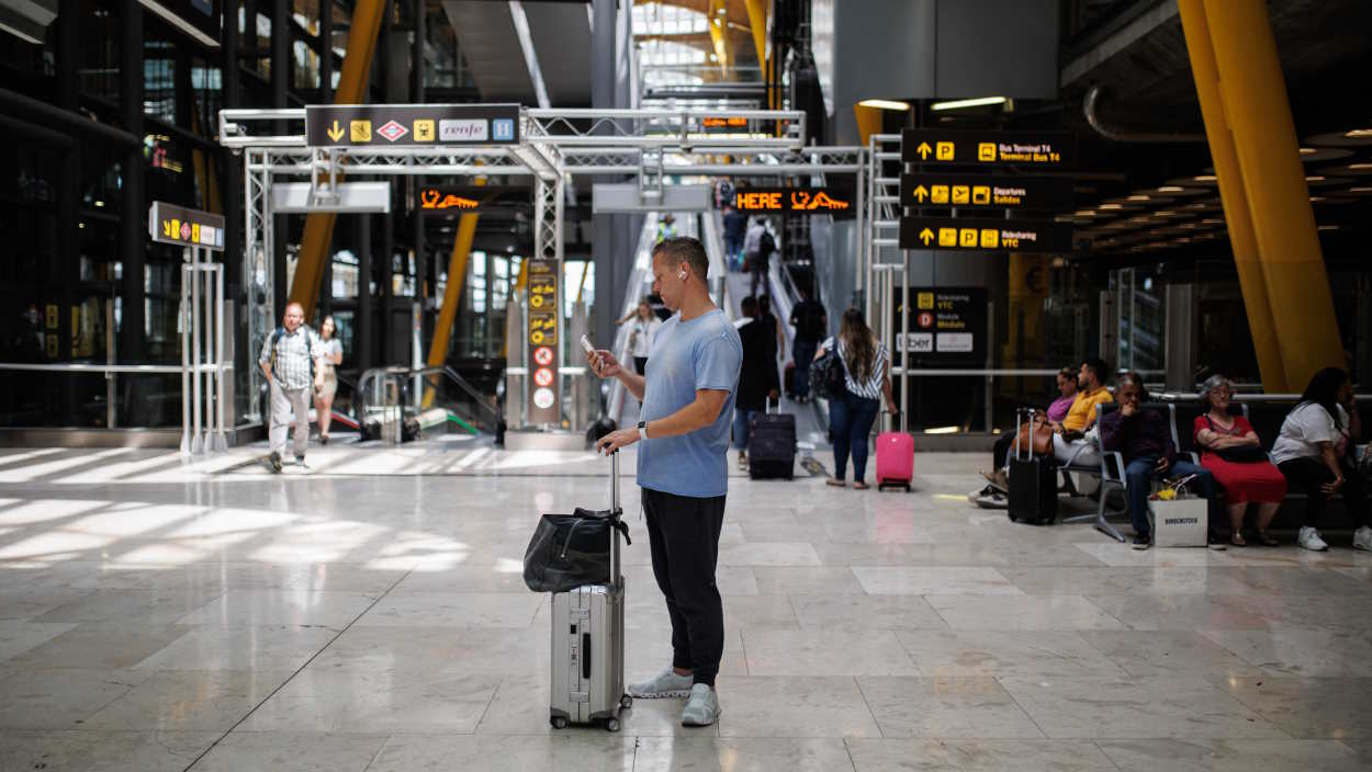Un hombre consulta su móvil en el aeropuerto. EP