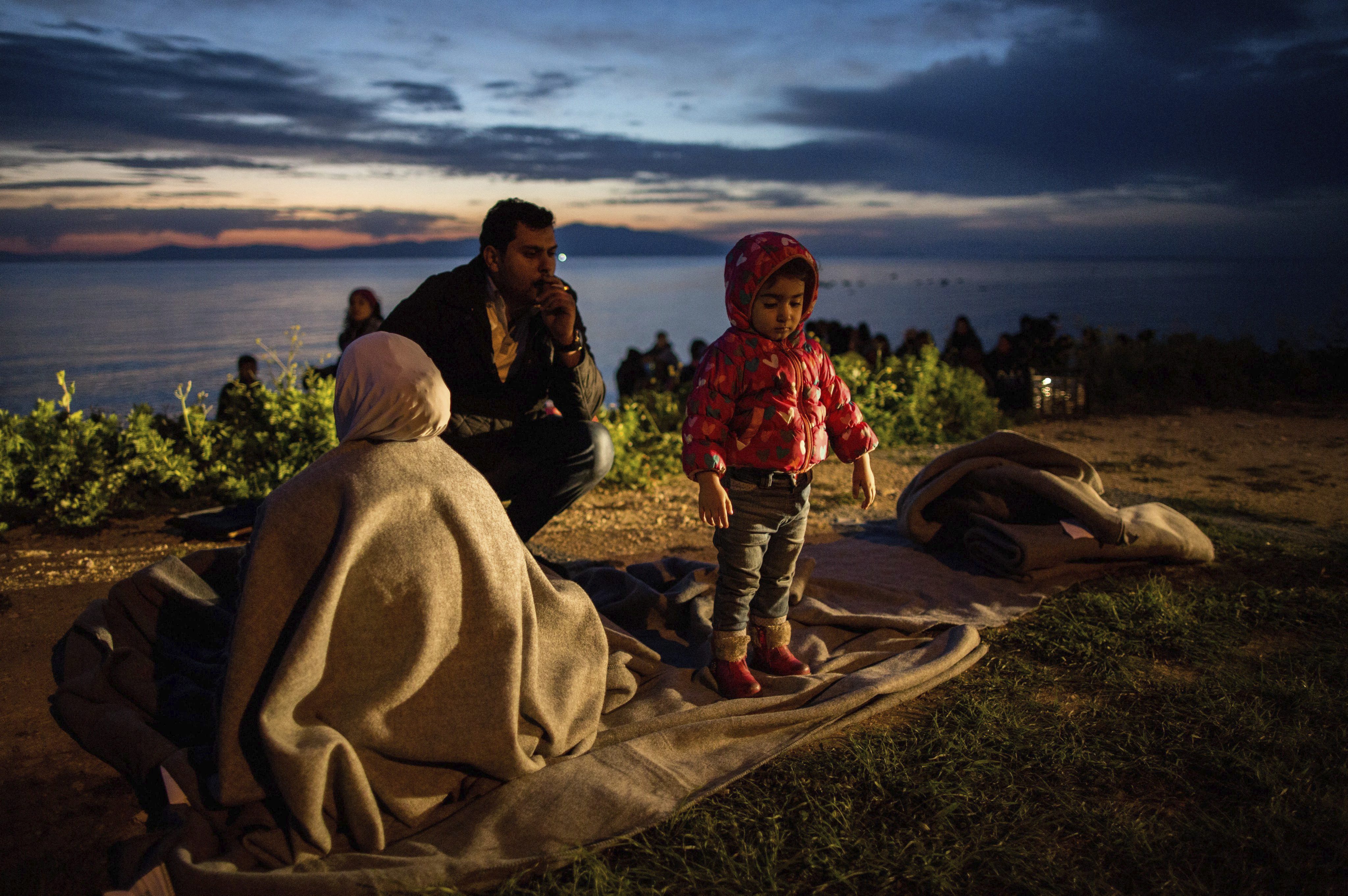 Una familia de refugiados descansa tras llegar a la isla de Lesbos tras cruzar el mar desde Turquía en el puerto de Mytilene (Grecia) hoy.