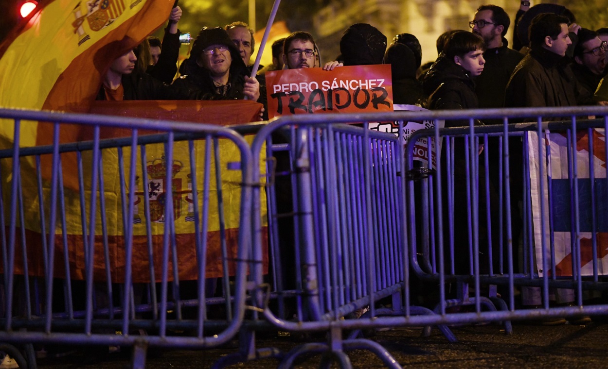 Decenas de personas portan banderas y carteles detrás de las vallas puestas por la Policía, durante una protesta en la calle Ferraz. EP.