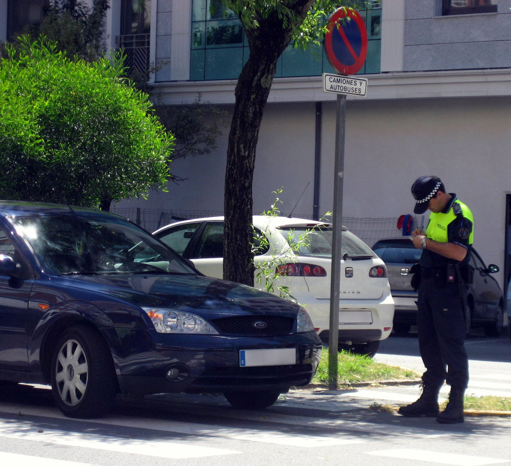 Un policía municipal multando a un coche por mal aparcamiento