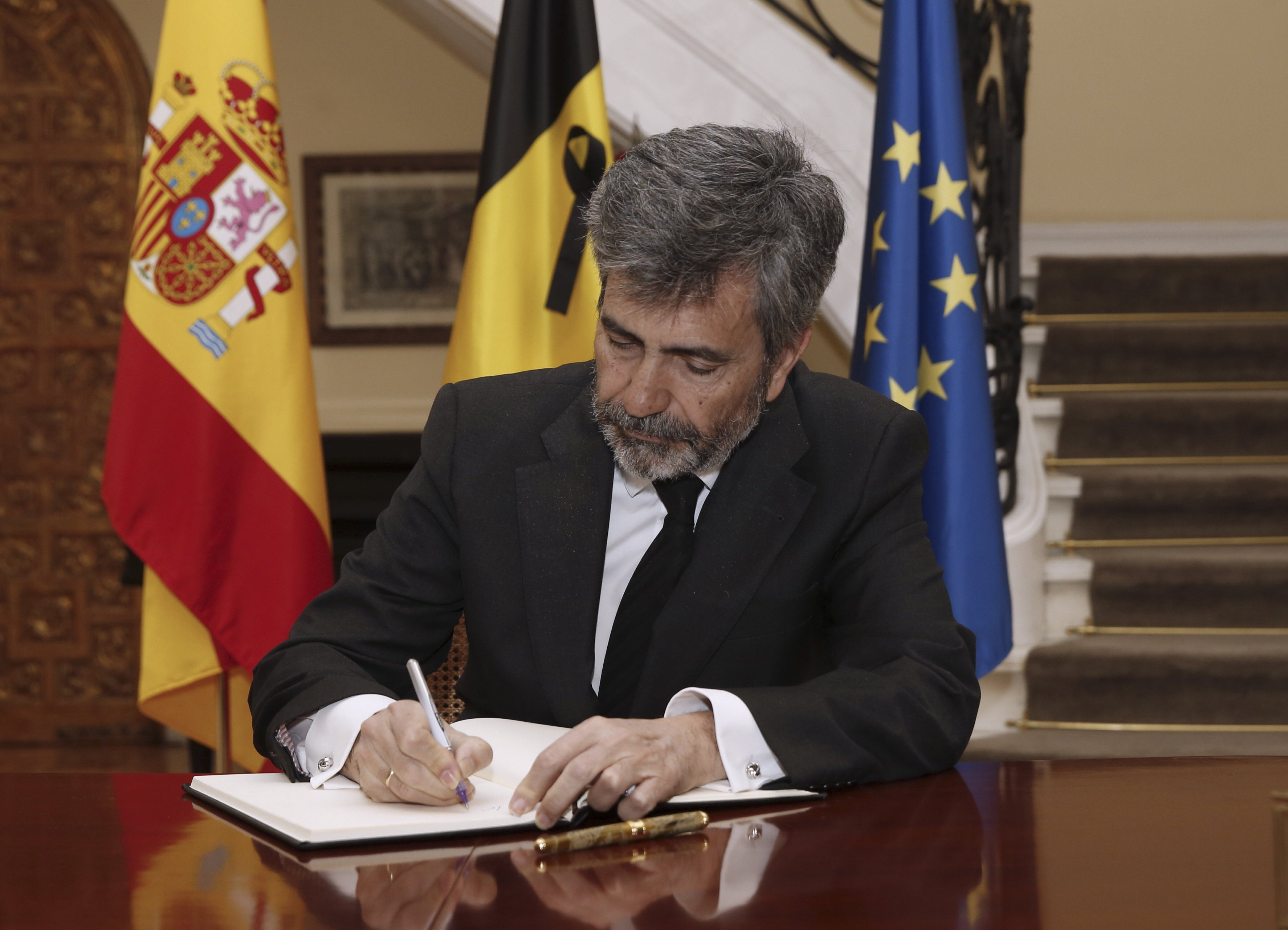 El presidente del Tribunal Supremo, Carlos Lesmes, firma en el libro de condolencias que se ha abierto en la residencia del embajador, con motivo de los atentados cometidos ayer en la capital belga. 