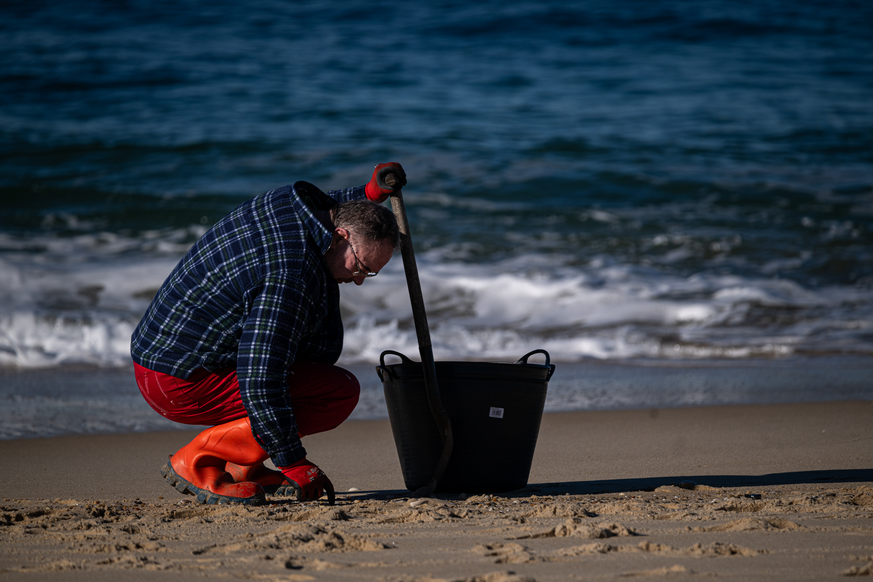 Un hombre recoge pellets en la playa