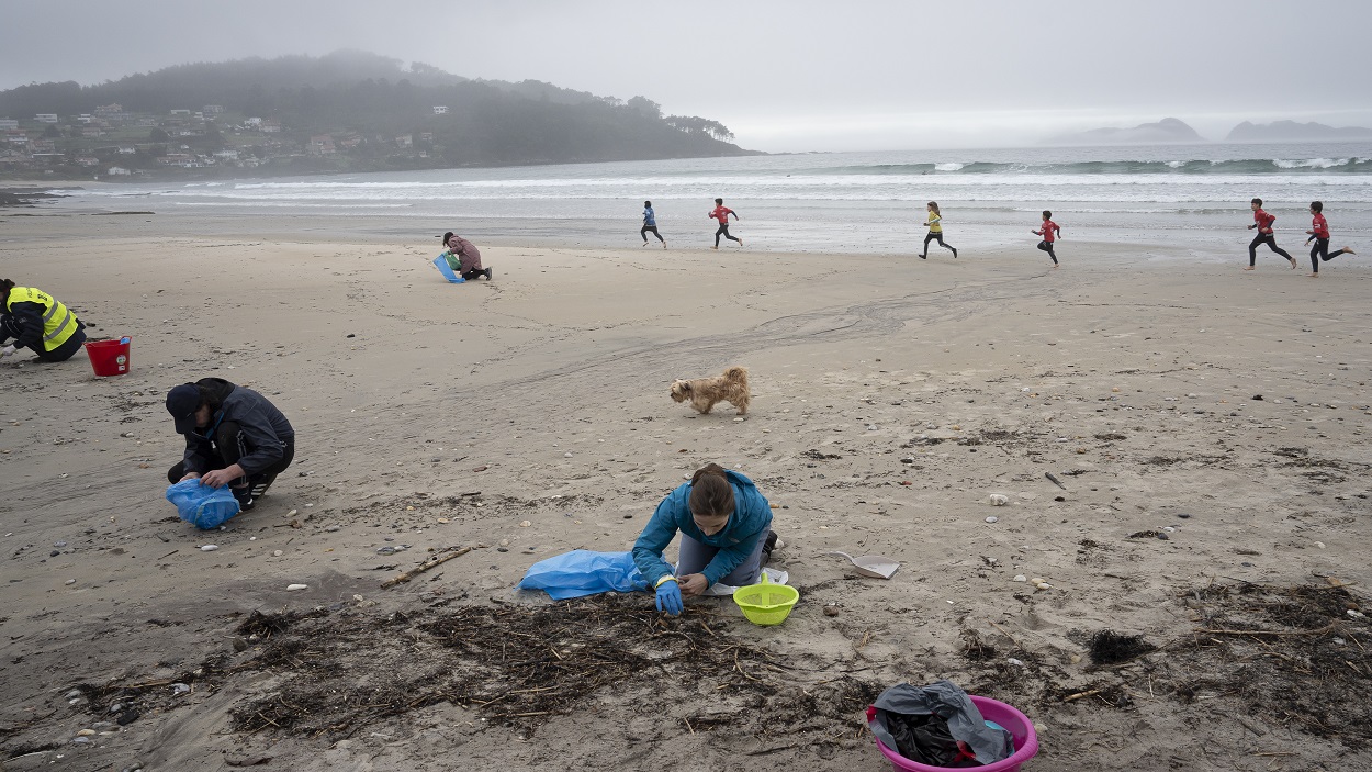 Voluntarios recogen pellets de plástico en una playa de Pontevedra (Galicia)