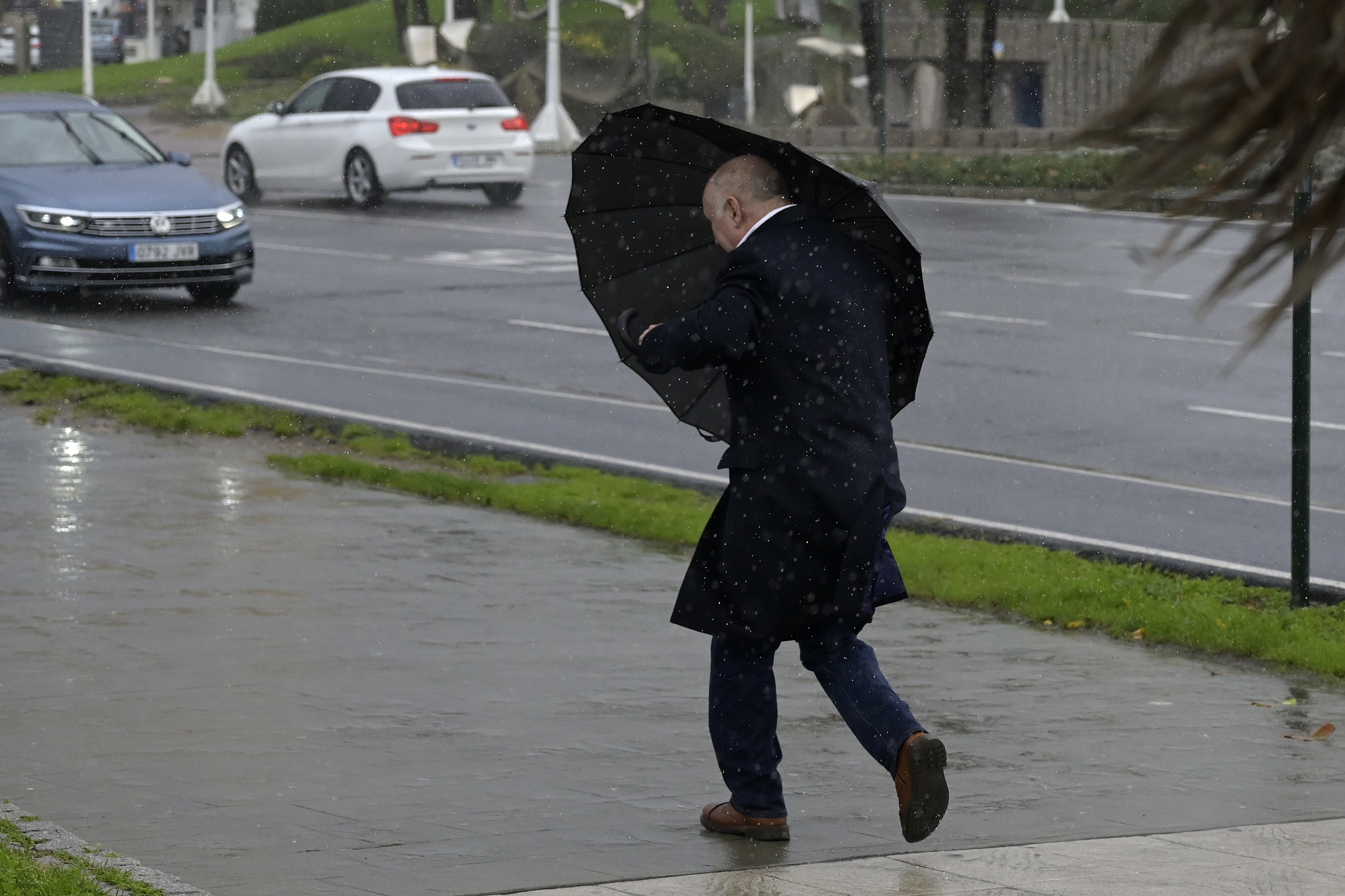 Un hombre se protege de la lluvia y el viento con un paraguas. EP