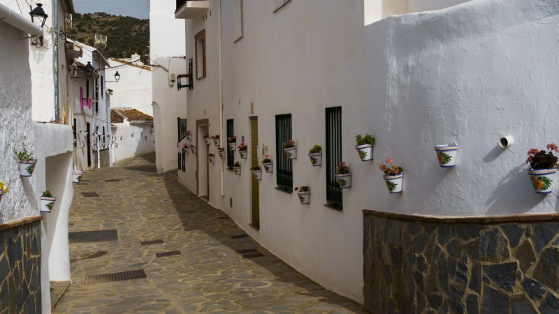 Calles empedradas y casas blancas adornadas con flores en Parauta, Málaga.