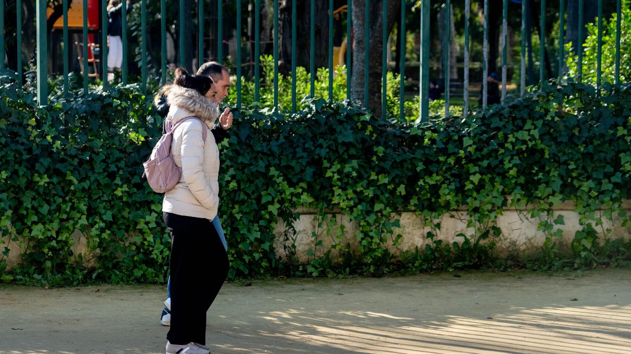 Dos personas caminan abrigadas por un parque en Sevilla. EP. 