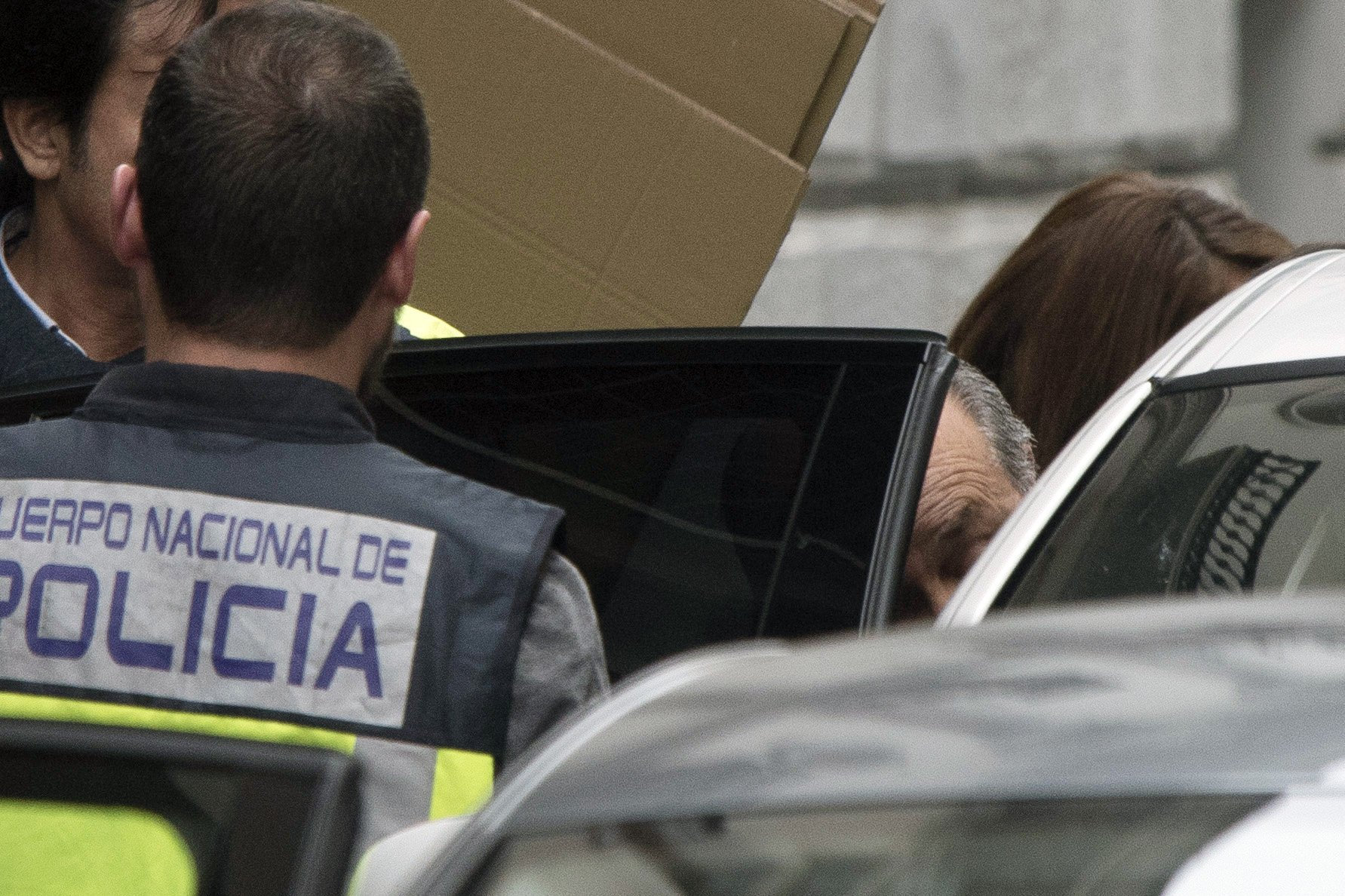 El alcalde de Granada, José Torres Hurtado (PP) (d), en el momento en entrar en el coche, tapado con cartones, tras abandonar el Ayuntamiento. (EFE)