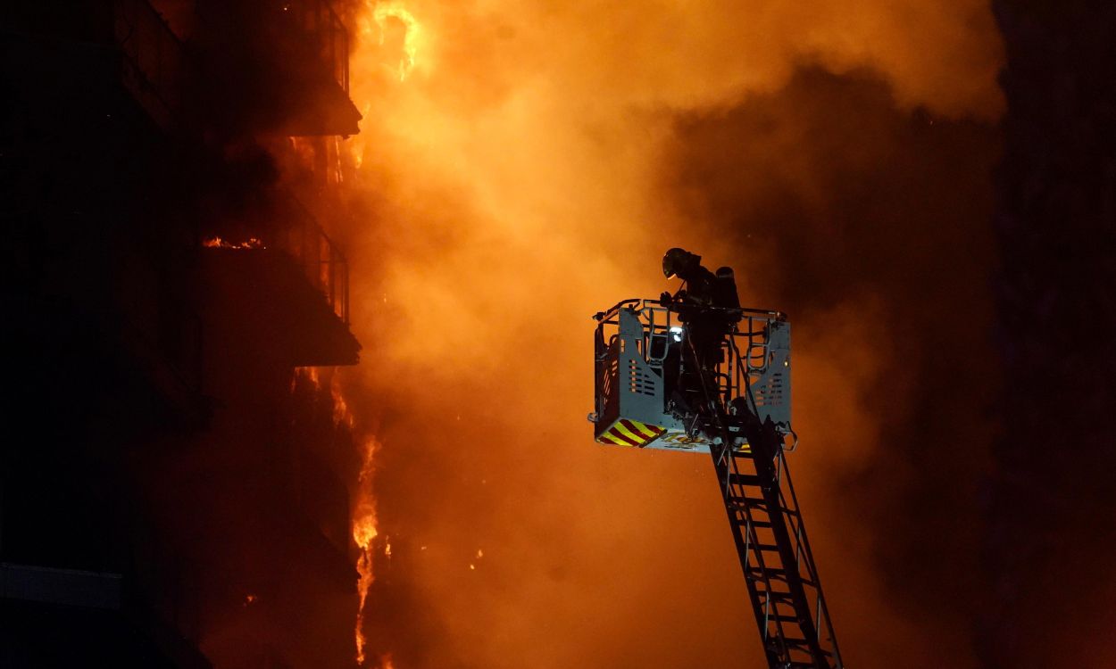 Un bombero sofocando las llamas del edificio incendiado de Valencia. EP.