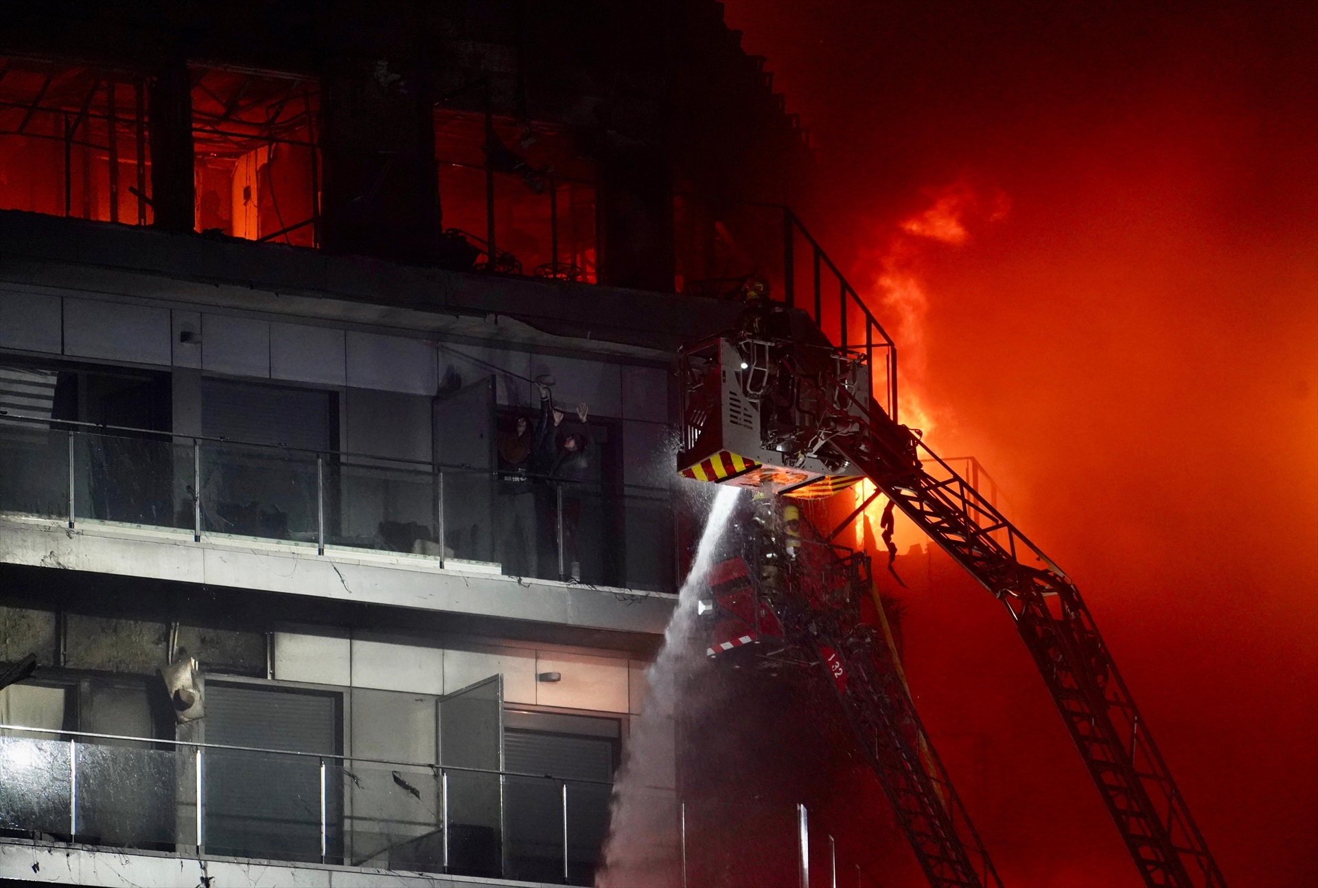 Un bombero trata de apagar el edificio en llamas con dos personas en un balcón, en el barrio de Campanar, a 22 de febrero de 2024, en Valencia, Comunidad Valenciana (España).