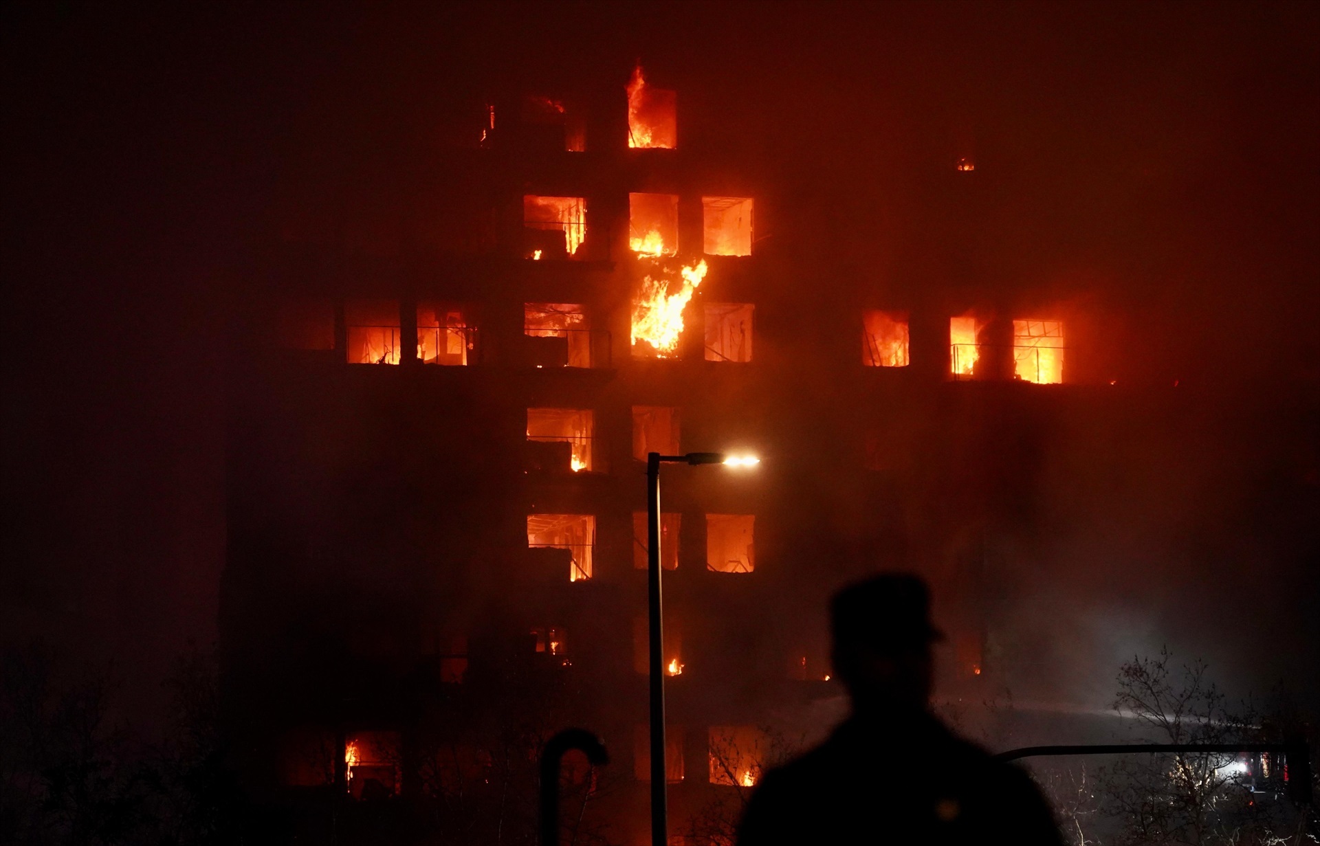 Un agente observa el edificio en llamas, en el barrio de Campanar, a 22 de febrero de 2024, en Valencia, Comunidad Valenciana (España). 