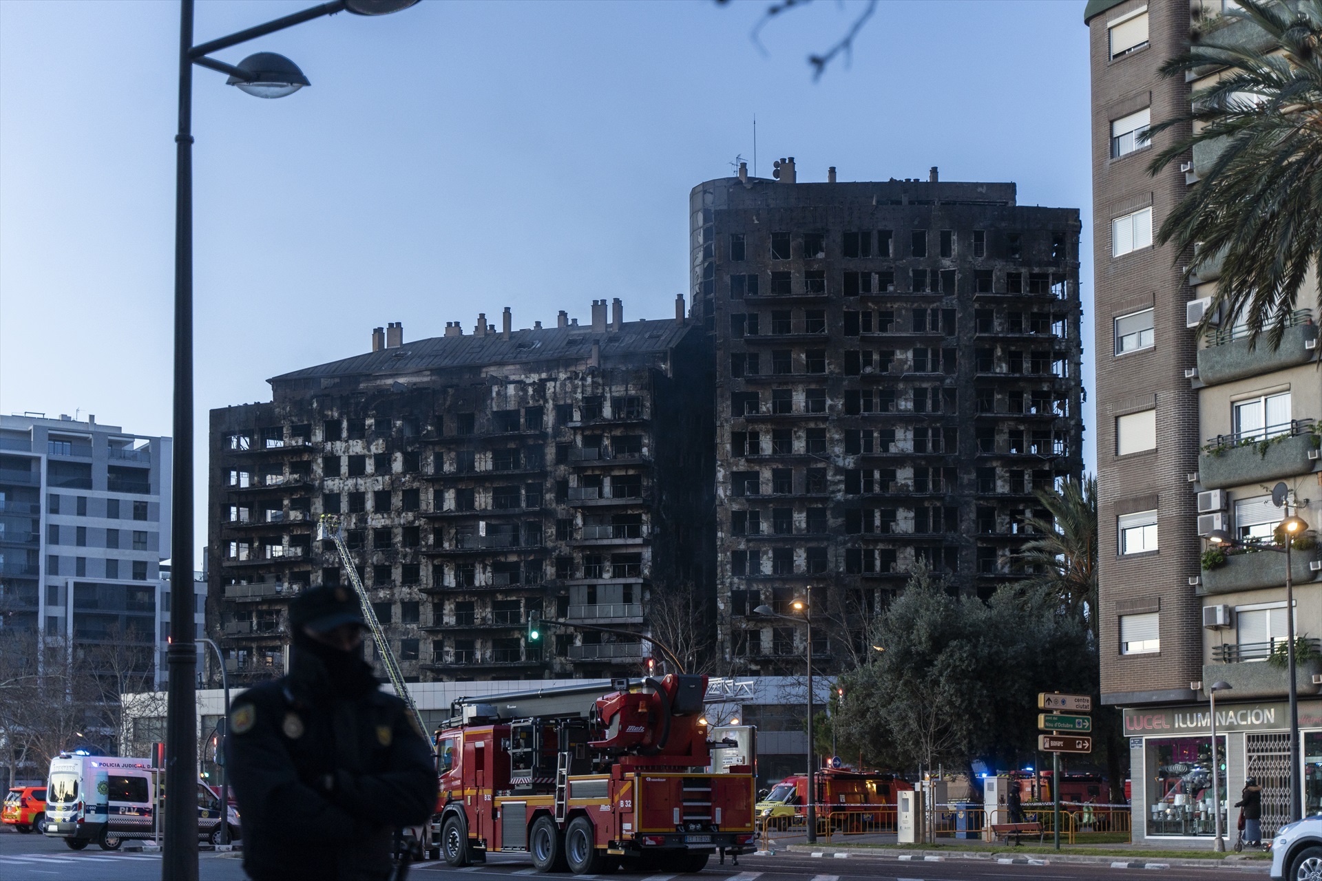 Bomberos y un agente de Policía Nacional en las inmediaciones de un edificio incendiado ayer, 22 de febrero, en el barrio de Campanar, a 23 de febrero de 2024, en Valencia, Comunidad Valenciana (España). 