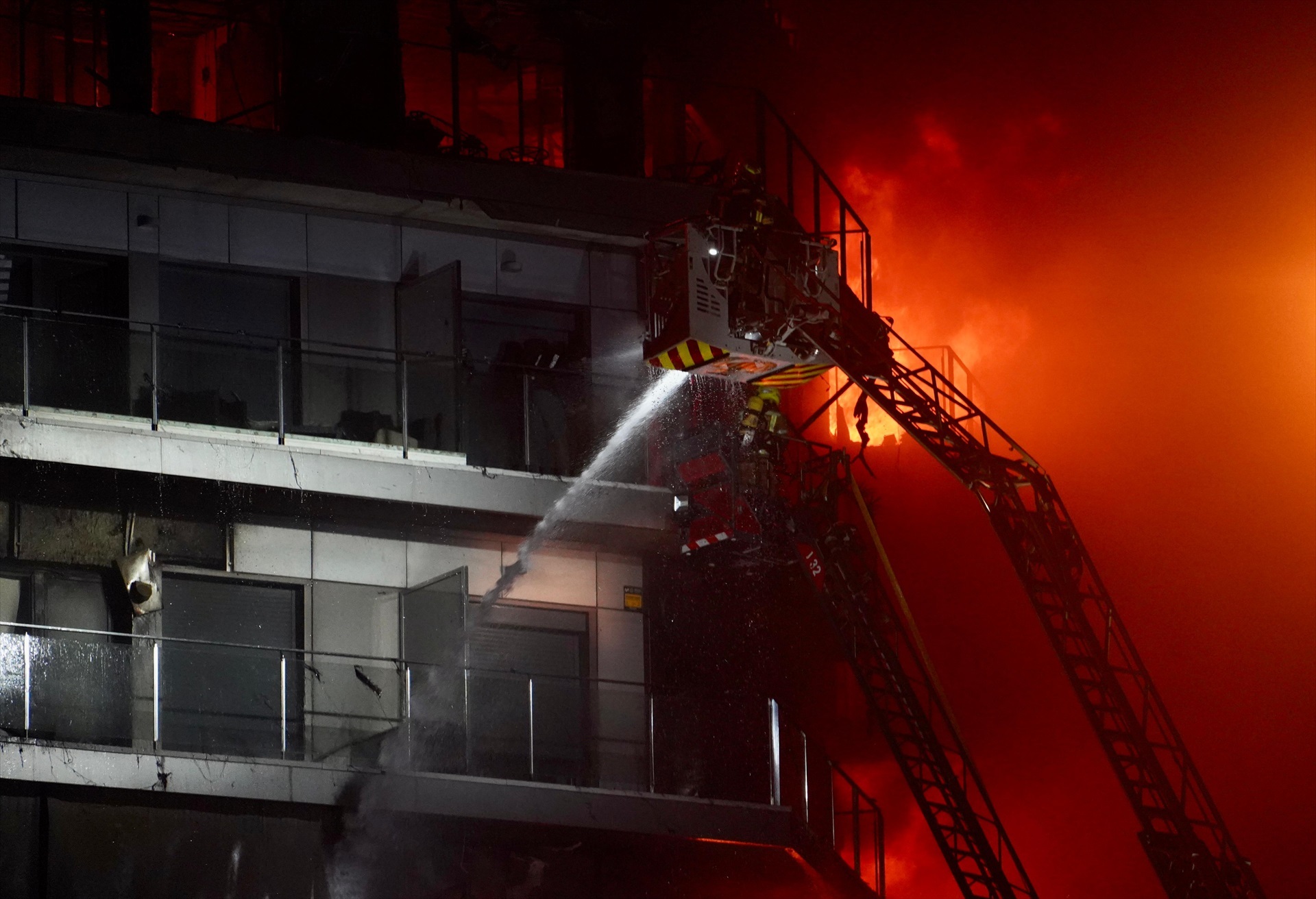 Dos bomberos tratan de apagar el edificio en llamas, en el barrio de Campanar, a 22 de febrero de 2024, en Valencia, Comunidad Valenciana (España).
