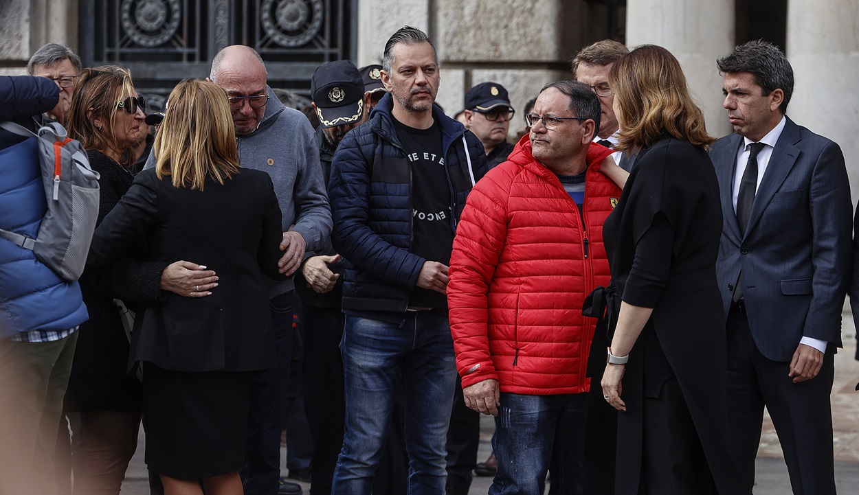 El presidente de la Comunidad Valenciana, Carlos Mazón (d), y la alcaldesa de Valencia, María José Catalá (2d), junto a familiares y vecinos de los fallecidos y el portero del edificio, Julián (3d), durante el minuto de silencio por las víctimas del incendio del barrio de Campanar. EP.