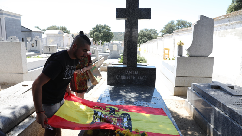 Un joven extiende una bandera preconstitucional sobre la tumba del expresidente del Gobierno Luis Carrero Blanco, en el cementerio de El Pardo - Mingorrubio | EP