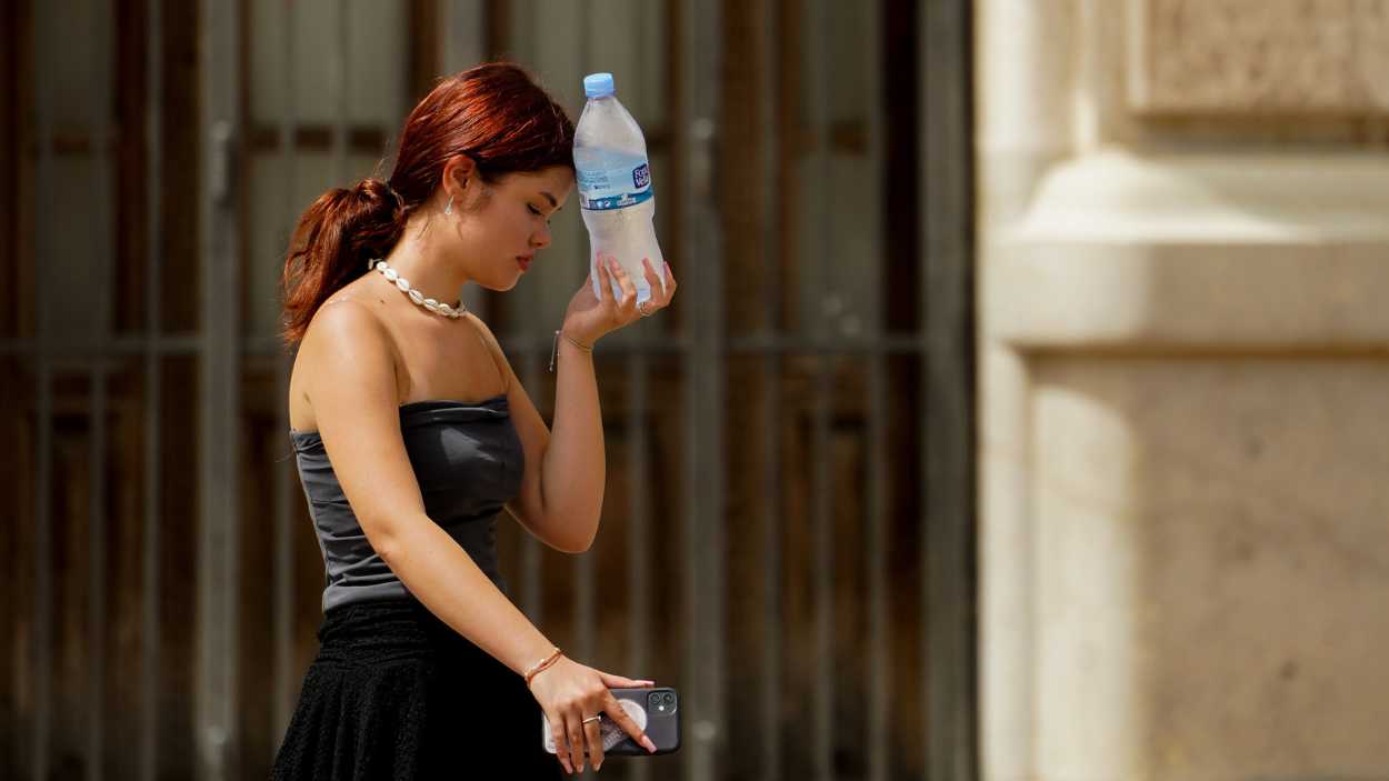 Una mujer caminando con una botella de agua. EP