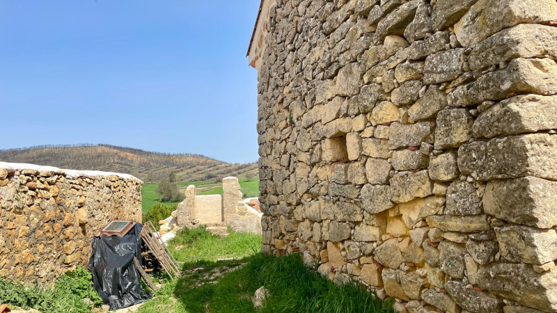 Obras de reconstrucción de edificios en Quintanilla del Coco. Al fondo, el monte quemado. F. V.