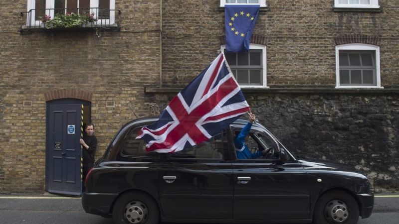 Un taxi pasea la bandera británica en Londres delante de una vivienda con la europea. Un taxi pasea la bandera británica en Londres delante de una vivienda con la europea.