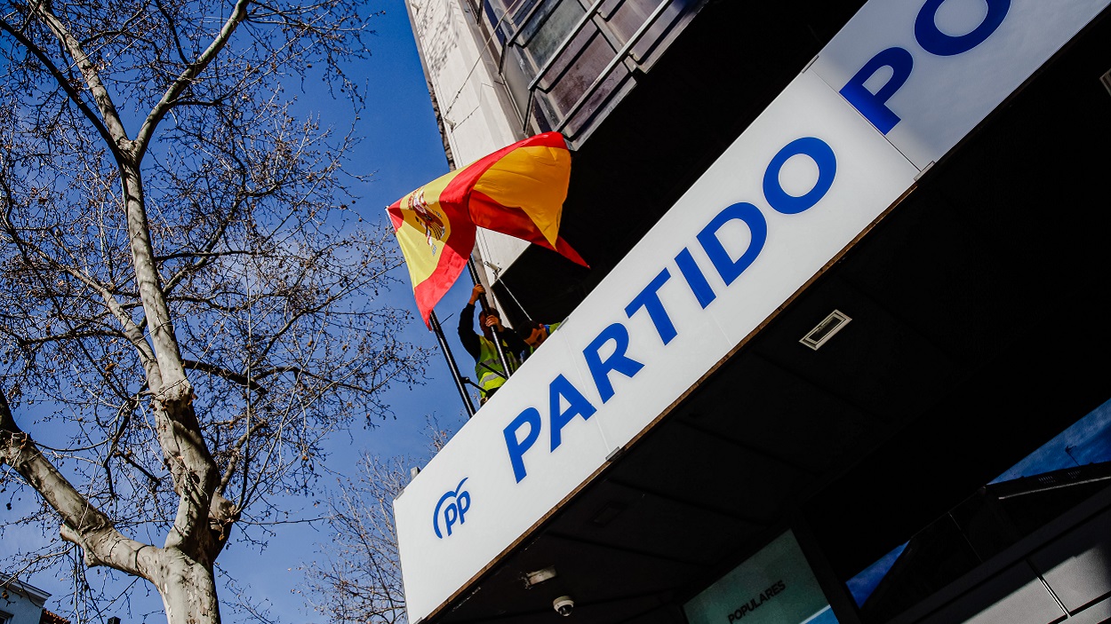 Dos trabajadores colocan una bandera de España en la sede del PP de la calle Génova. EP/Archivo.