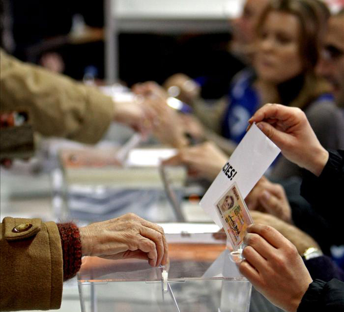Una mujer deposita su voto en una urna electoral.