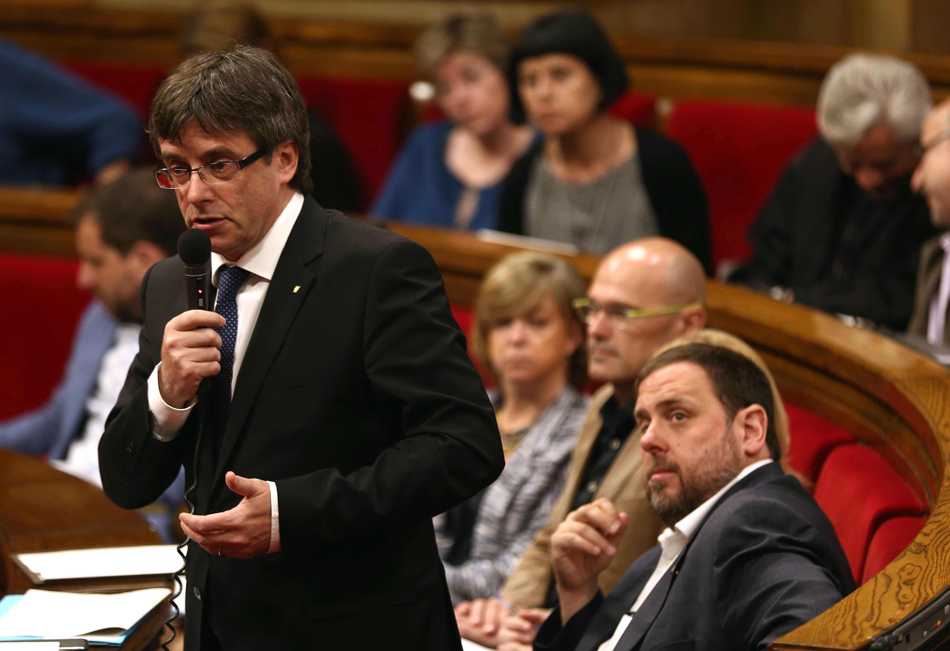 El presidente de la Generalitat, Carles Puigdemont, ante la mirada de Raül Romeva y Oriol Junqueras.