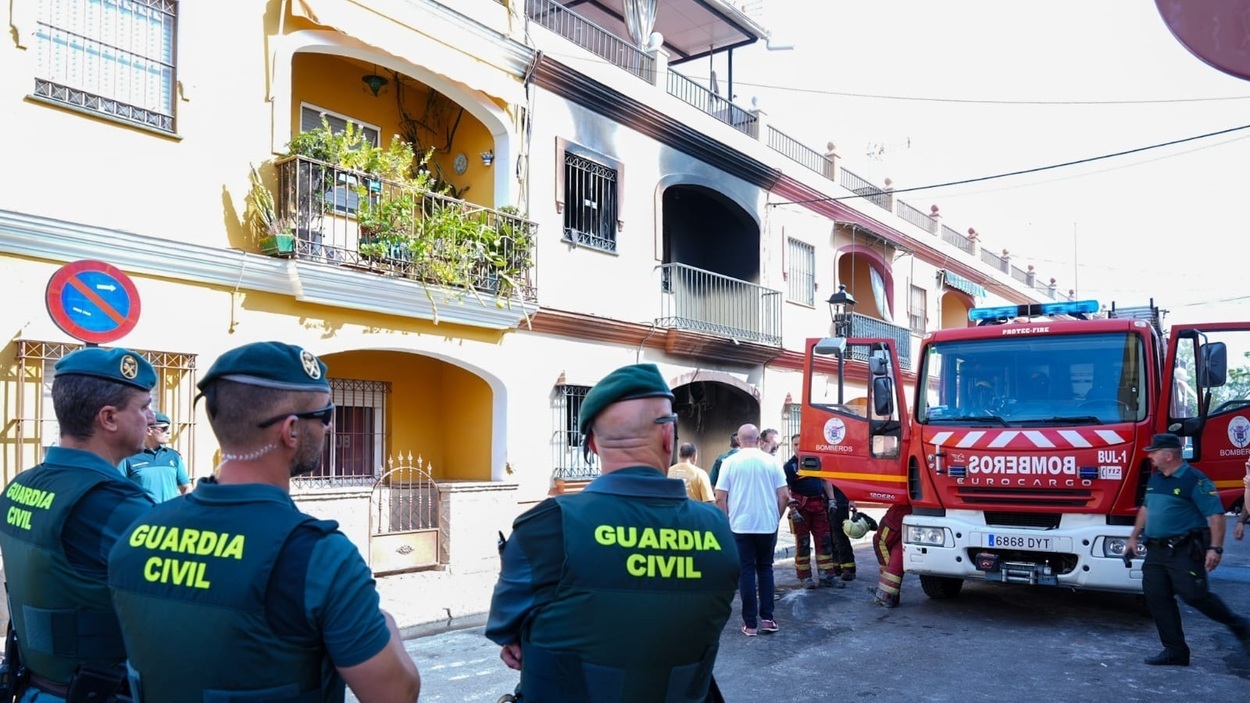 Agentes de la Guardia Civil y Bomberos en la calle frente a la casa incendiada. EP