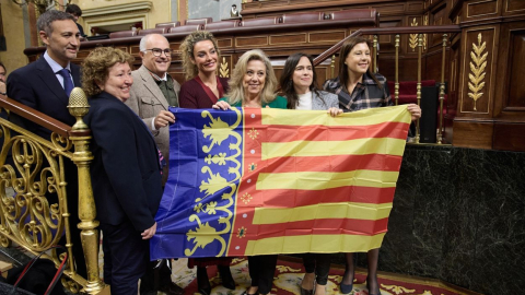 Diputados de grupos parlamentarios valencianos con una bandera de la Generalitat valenciana por el Día de la Generalitat, durante una sesión de control al Gobierno, en el Congreso de los Diputados