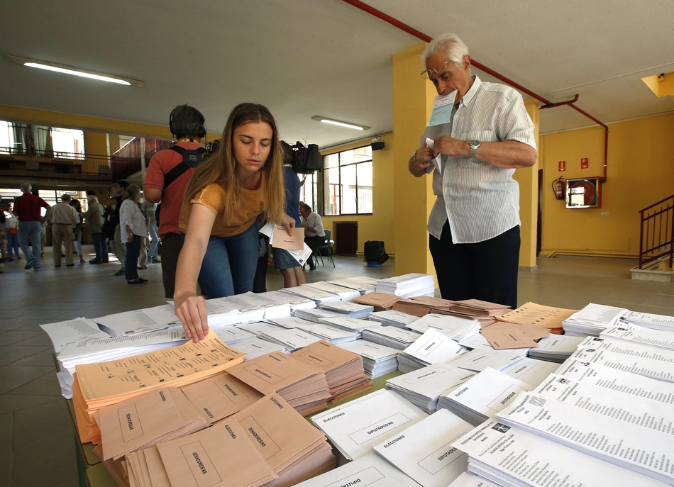 Una joven elige las papeletas antes de depositar su voto este domingo.