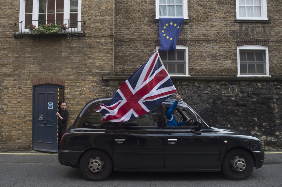 Un taxi pasea la bandera británica en Londres delante de una vivienda con la europea.