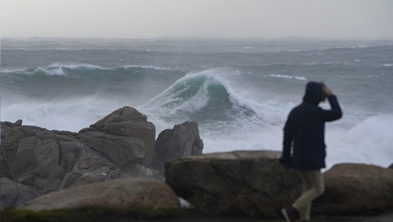 Una persona camina por el paseo marítimo observando el mar en A Coruña. EP
