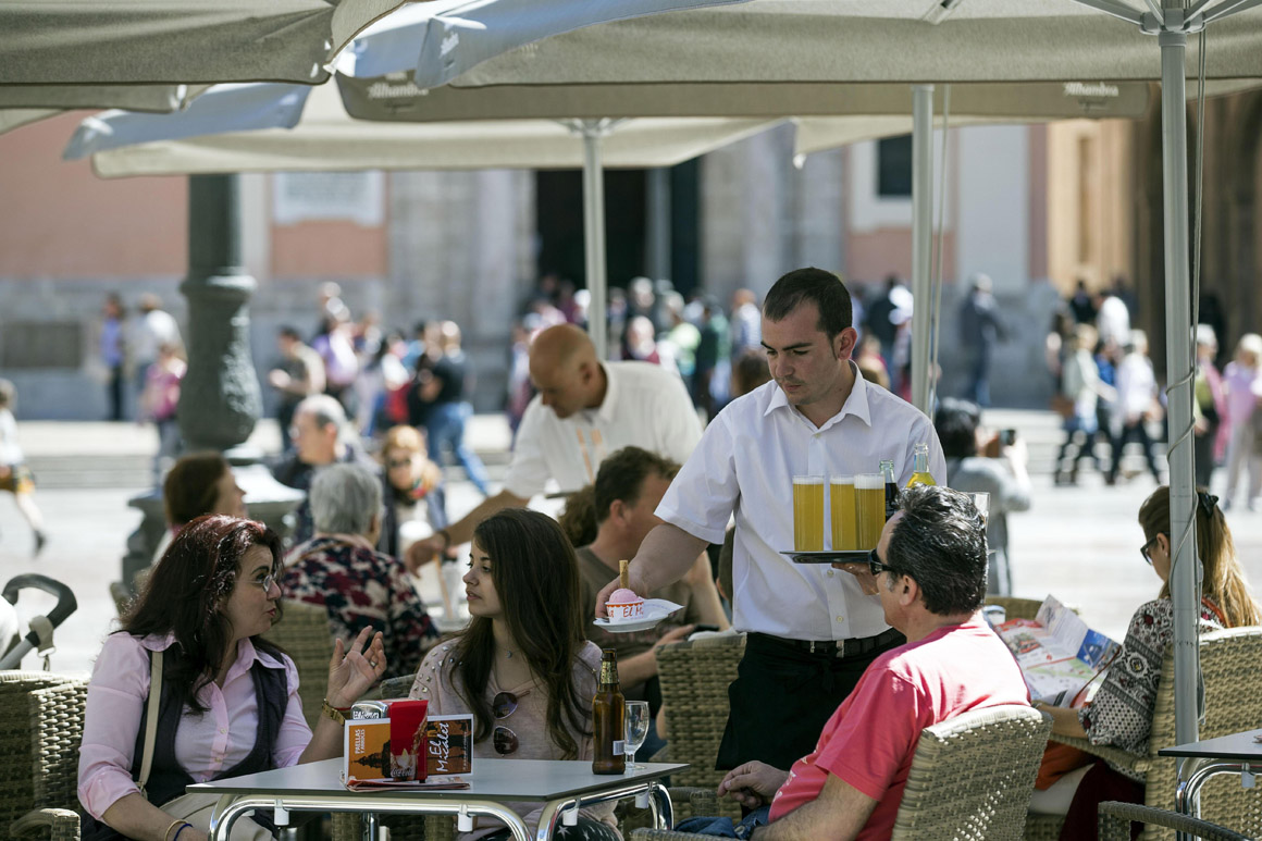 Un camarero sirve bebidas en una terraza en la plaza de la Virgen de Valencia. 