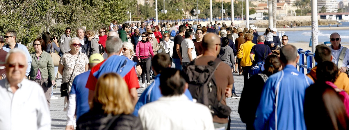 Una multitud de turistas disfrutando de un paseo junto a la playa