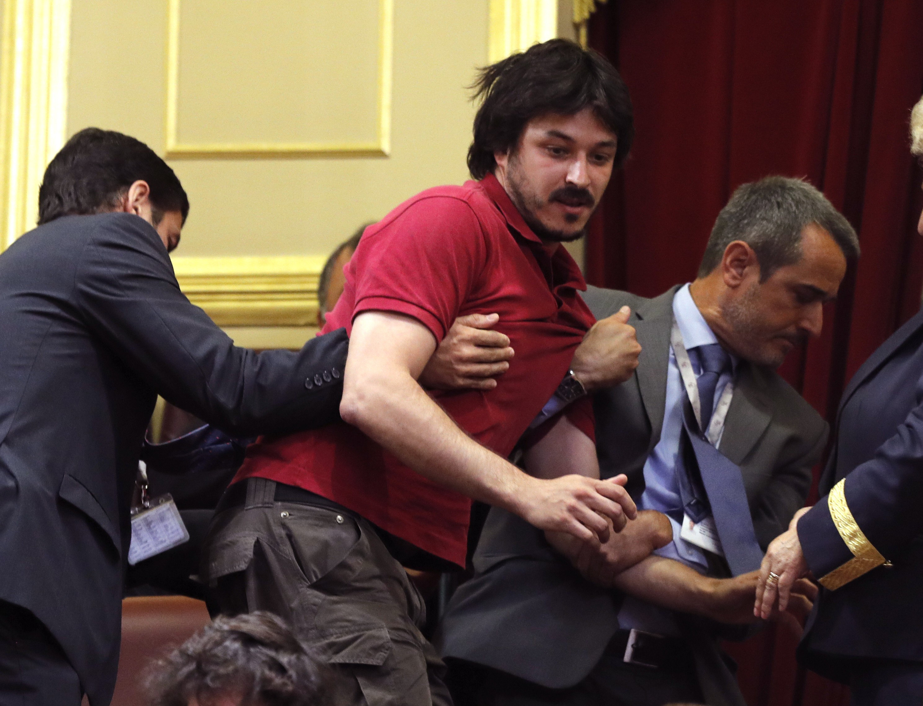 Victor Taibo es desalojado tras lanzar una octavilla reclamando justicia para las víctimas del accidente del tren Alvia de Santiago de Compostela, durante la sesión constitutiva de las Cortes Generales. 