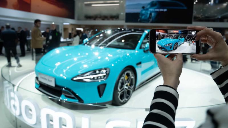 Una persona con un móvil en la presentación del coche Xiaomi SU7 en la edición 2024 del MWC. EP