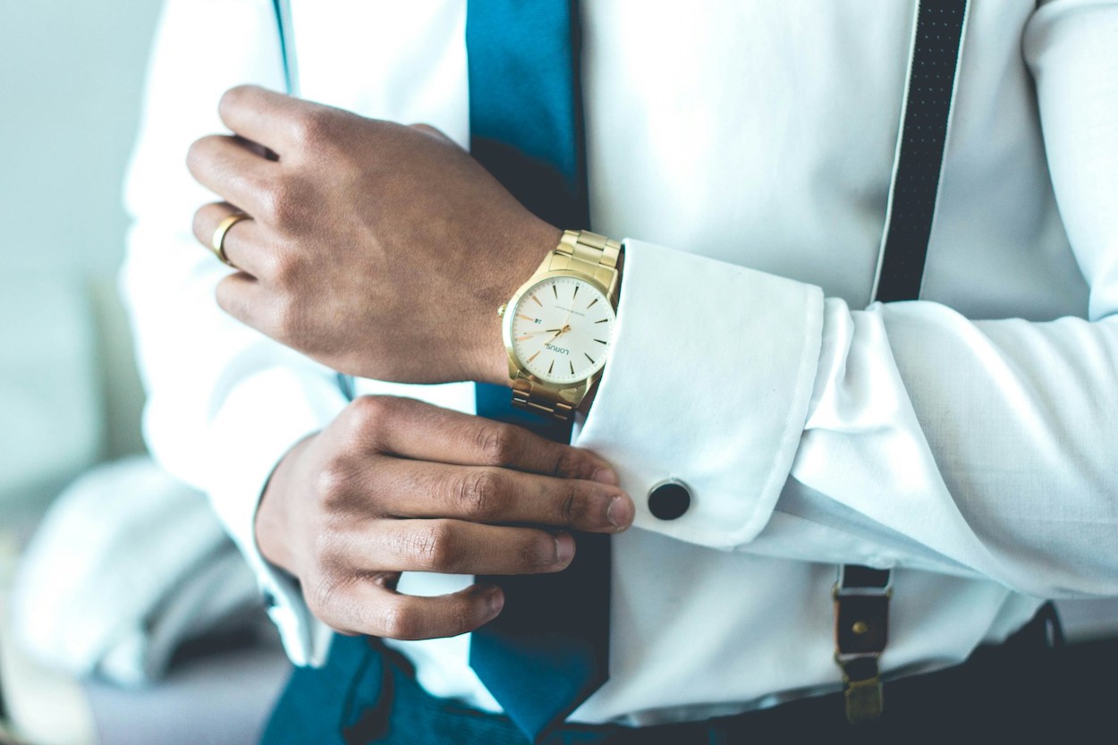 Empresario con reloj de oro se ajusta unos gemelos