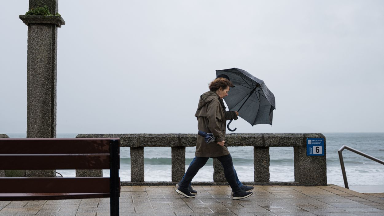 Mujer se refugia de la lluvia con paraguas. EP.