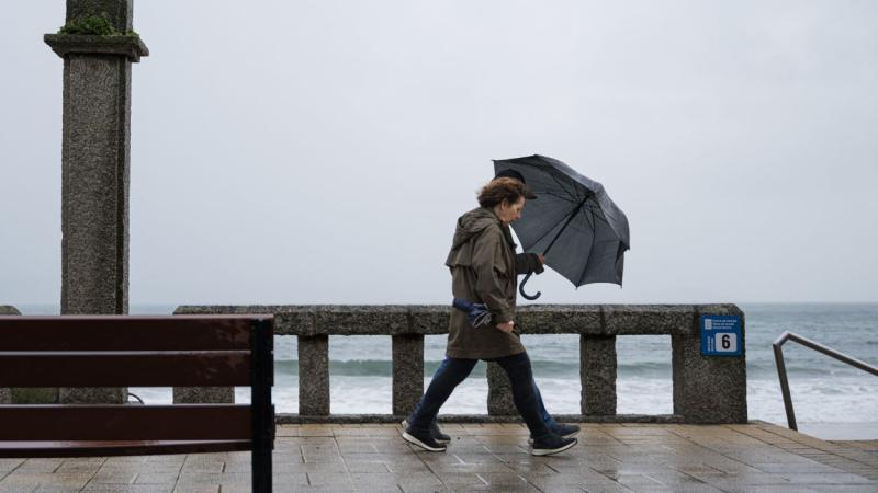 Mujer se refugia de la lluvia con paraguas. EP.
