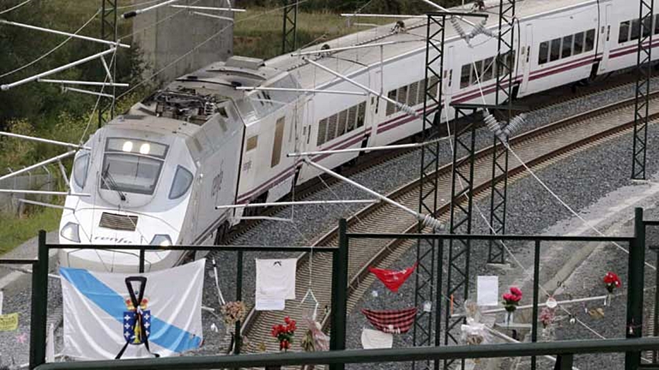 Un tren llegando a la curva de Angrois ante una bandera gallega con crespón negro. 