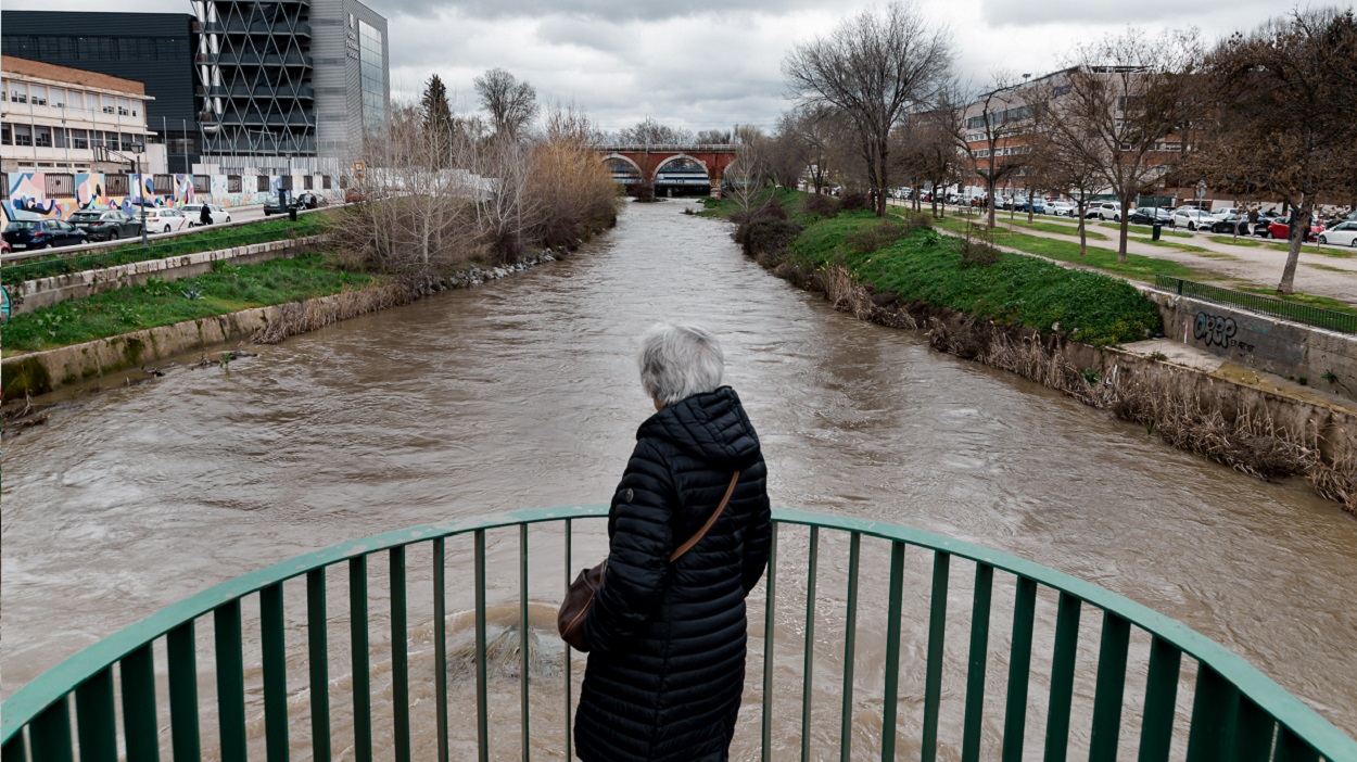 Una mujer observa la crecida del Río Manzanares tras las fuertes lluvias de marzo. EP