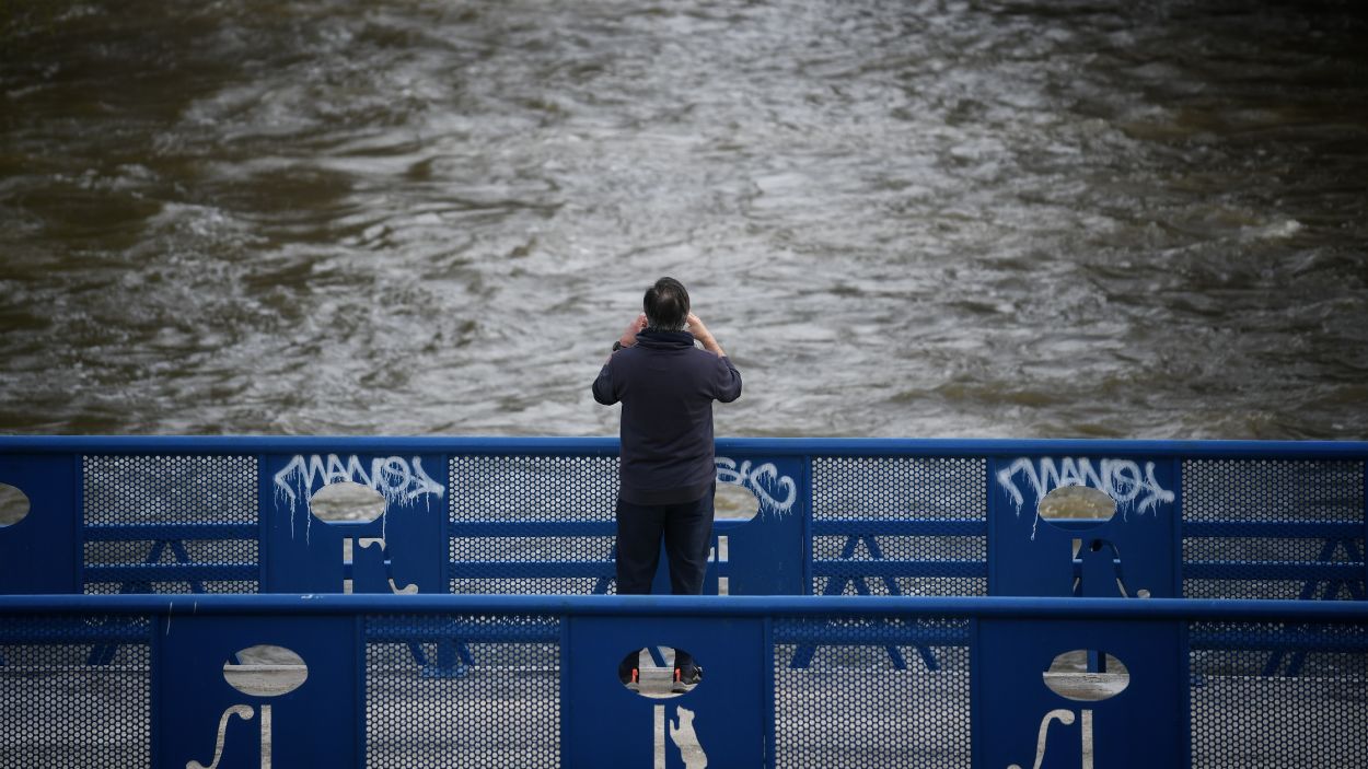 Una persona fotografía la crecida del río, en el parque lineal del Manzanares. EP