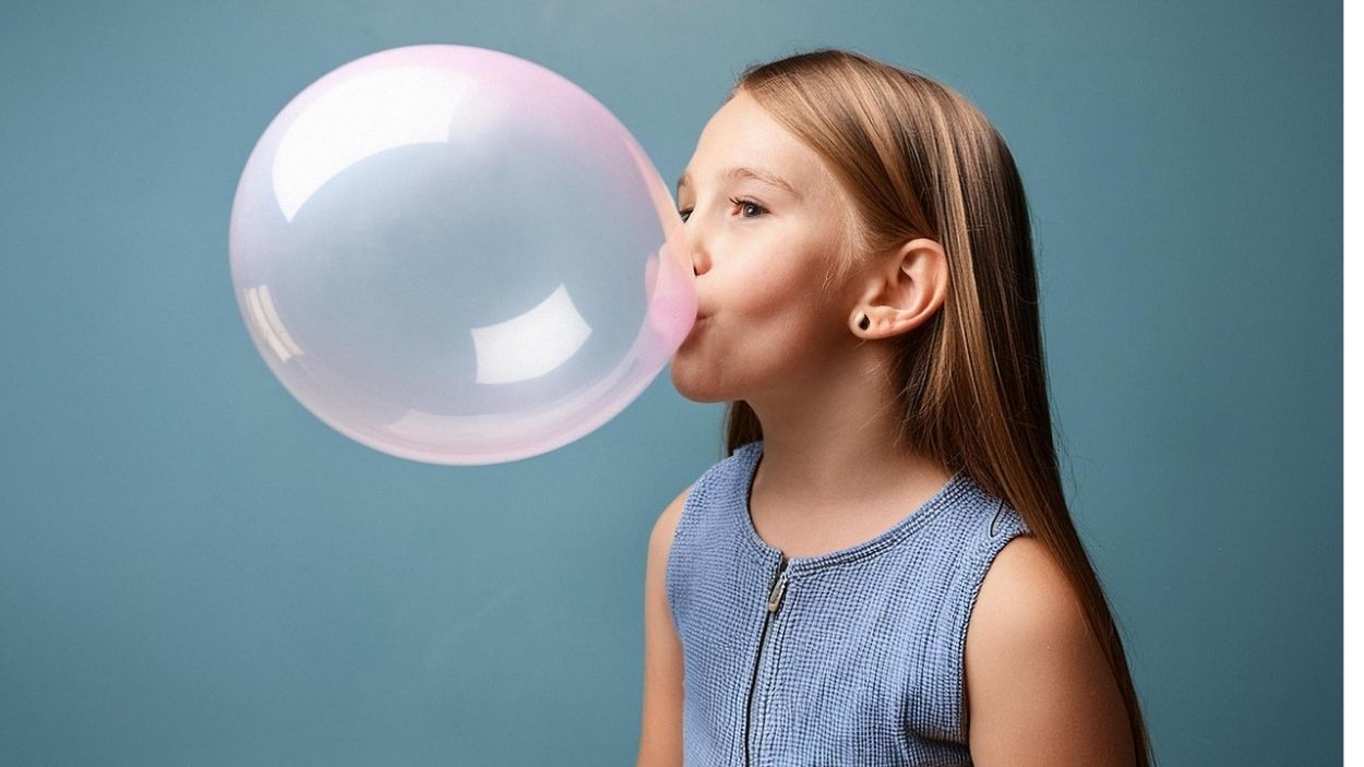 Una niña hace una burbuja con chicle. Pixaby