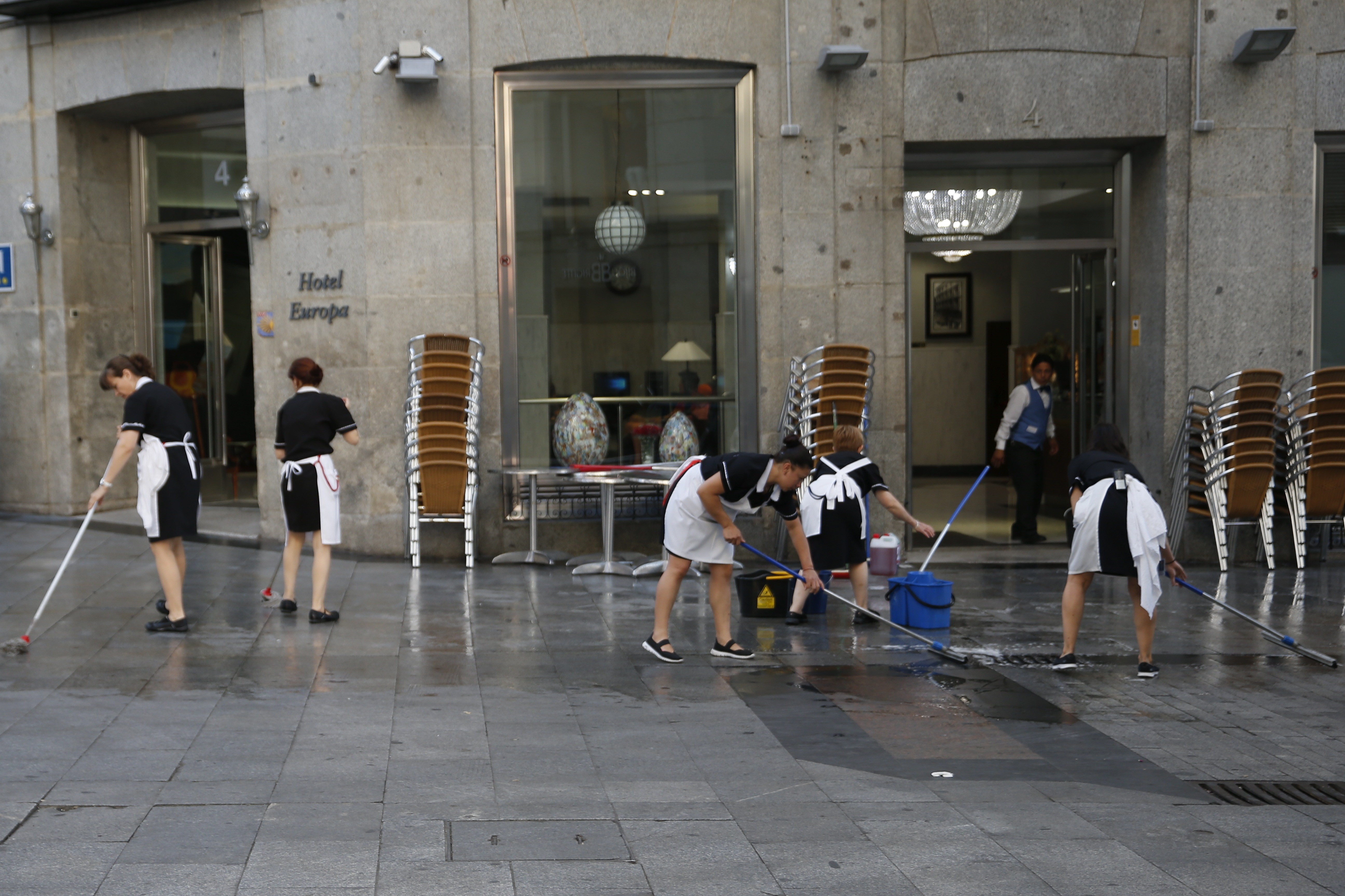 Un grupo de trabajadoras limpia la acera antes de montar la terraza de un hotel madrileño.