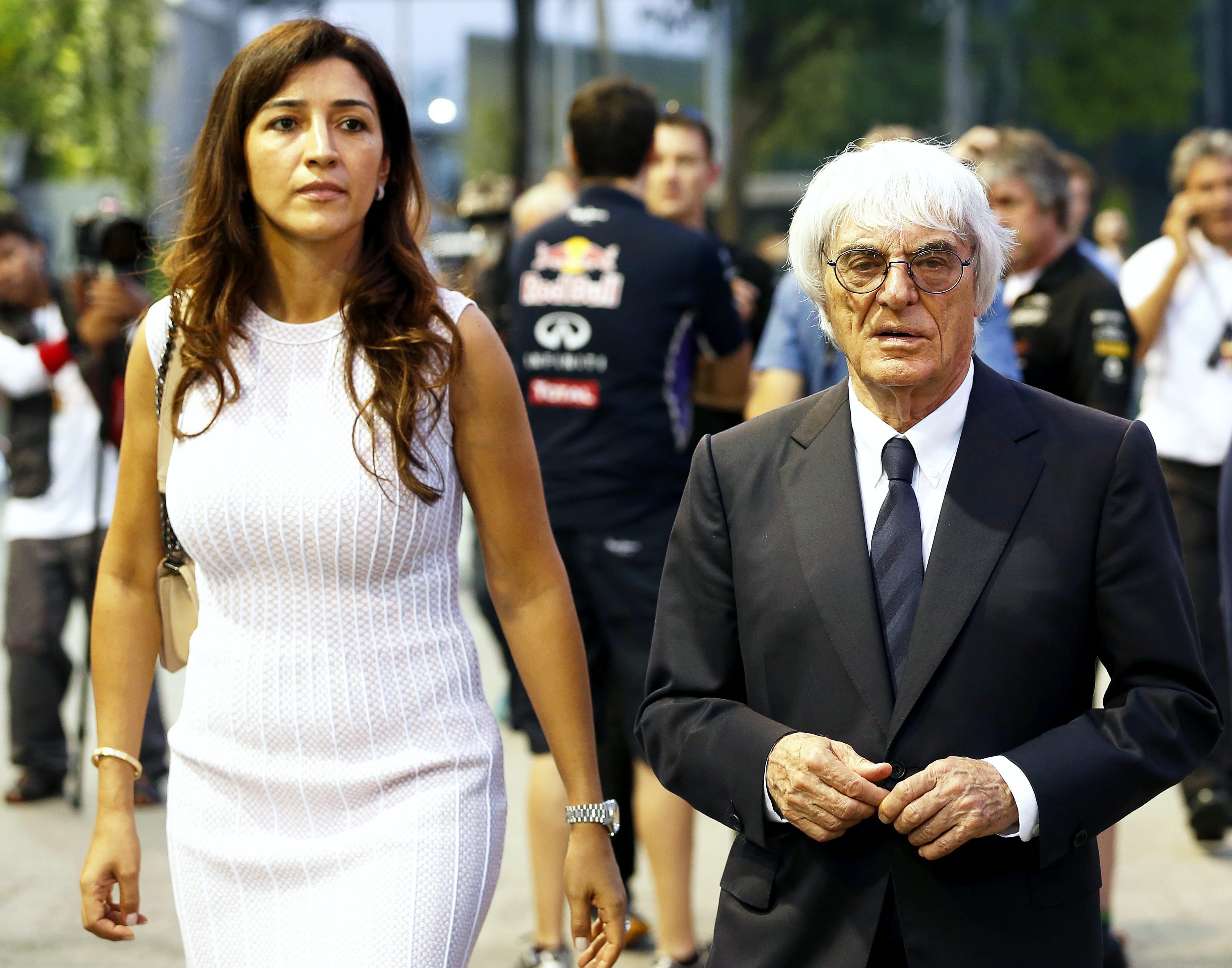 Fotografía de archivo fechada el 18 de septiembre de 2014 que muestra al máximo responsable de la Fórmula Uno, Bernie Ecclestone (d), y a su mujer Fabiana Flosi (izq), mientras caminan por el "paddock" del circuito de la Marina Bay Street, en Singapur. 