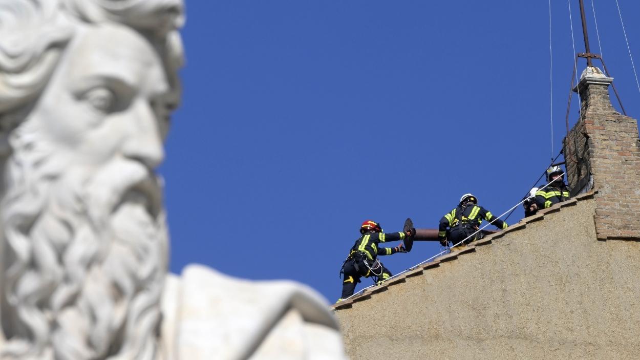 Los bomberos instalan en el tejado de la Capilla Sixtina la chimenea de la que saldrán las fumatas negras y blanca. EP