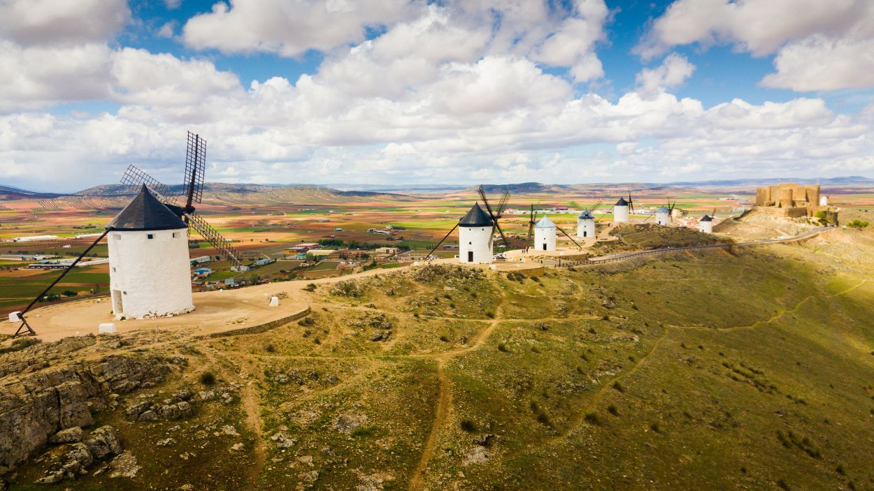 Una de las estampas más reconocidas de los pueblos de Castilla-La Mancha es este cerro Calderico, en Consuegra (Toledo), con sus imponentes molinos de viento y el castillo medieval al fondo