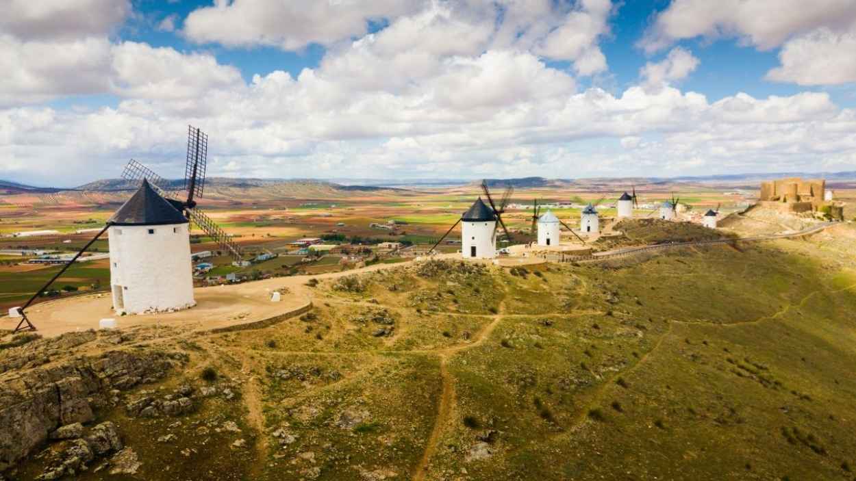 Una de las estampas más reconocidas de los pueblos de Castilla-La Mancha es este cerro Calderico, en Consuegra (Toledo), con sus imponentes molinos de viento y el castillo medieval al fondo